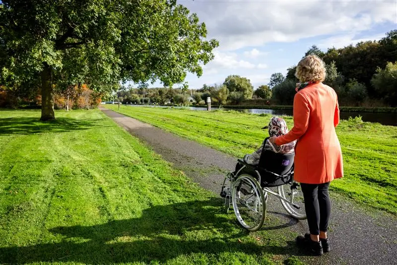 Vrijwilliger van Topaz samen met een bewoner aan het wandelen Vrijwilliger van Topaz samen met een bewoner aan het wandelen